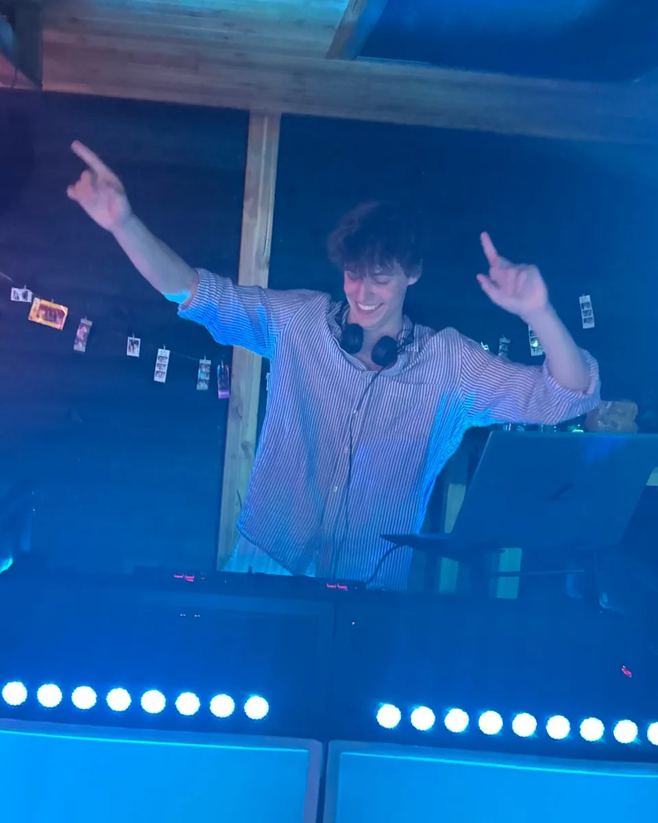 DJ Freez achter de draaitafels, met beide handen in de lucht